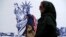 People walk past a satirical drawing of the Statue of Liberty after new anti-U.S. murals on the walls of the former U.S. Embassy were unveiled in a ceremony in Tehran, Iran, Nov. 2, 2019. 