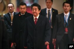 Japan's Prime Minister Shinzo Abe, center, leaves after a bilateral meeting with South Korean President Moon Jae-in, at hotel on the sidelines of the trilateral leaders' meeting between China, South Korea and Japan in China.