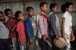FILE - Children, who fled the violence in Ethiopia's Tigray region, wait in line for breakfast organized by a self-volunteer, in Mekelle, the capital of Tigray region, June 23, 2021.