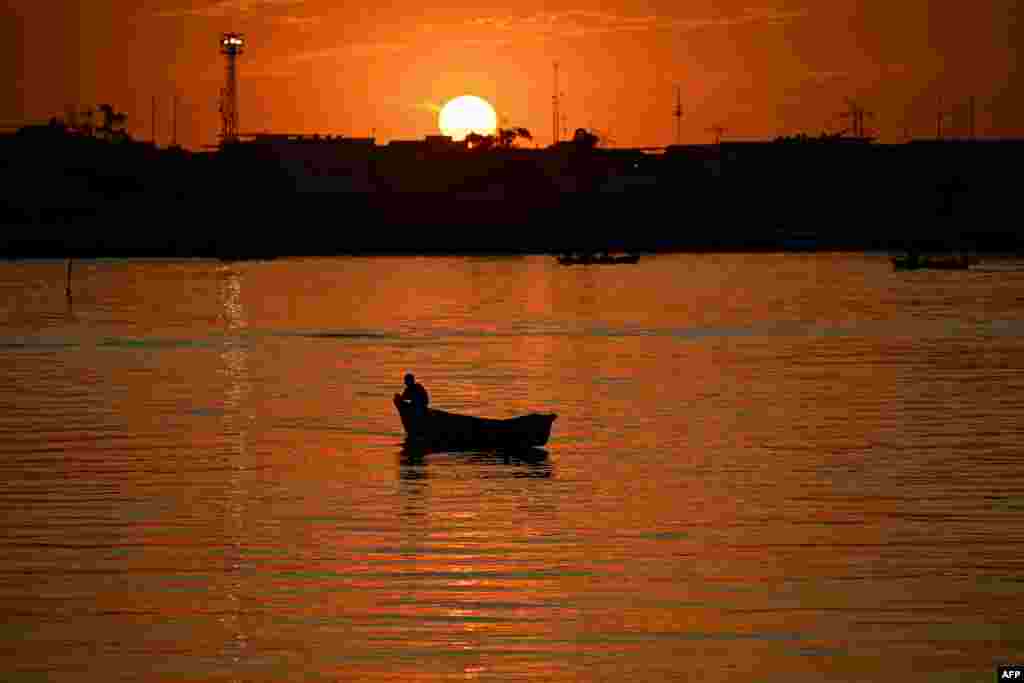 Siluet seorang nelayan Irak berlayar saat matahari terbenam di sepanjang Sungai Shatt al-Arab, yang terbentuk dari pertemuan sungai Tigris dan Efrat, di kota Basra, Irak selatan. (AFP)&nbsp;