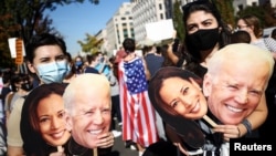 ពលរដ្ឋអាមេរិកាំងកាន់បដារូបលោក Joe Biden និងអ្នកស្រី Kamala Harris បន្ទាប់ពីបណ្តាញផ្សាយព័ត៌មាន បានព្យាករណ៍ថាឈ្នះការបោះឆ្នោតប្រធានាធិបតីសហរដ្ឋអាមេរិក នៅក្បែរសេតវិមាន ថ្ងៃទី៧ ខែវិច្ឆិកា ឆ្នាំ២០២០។