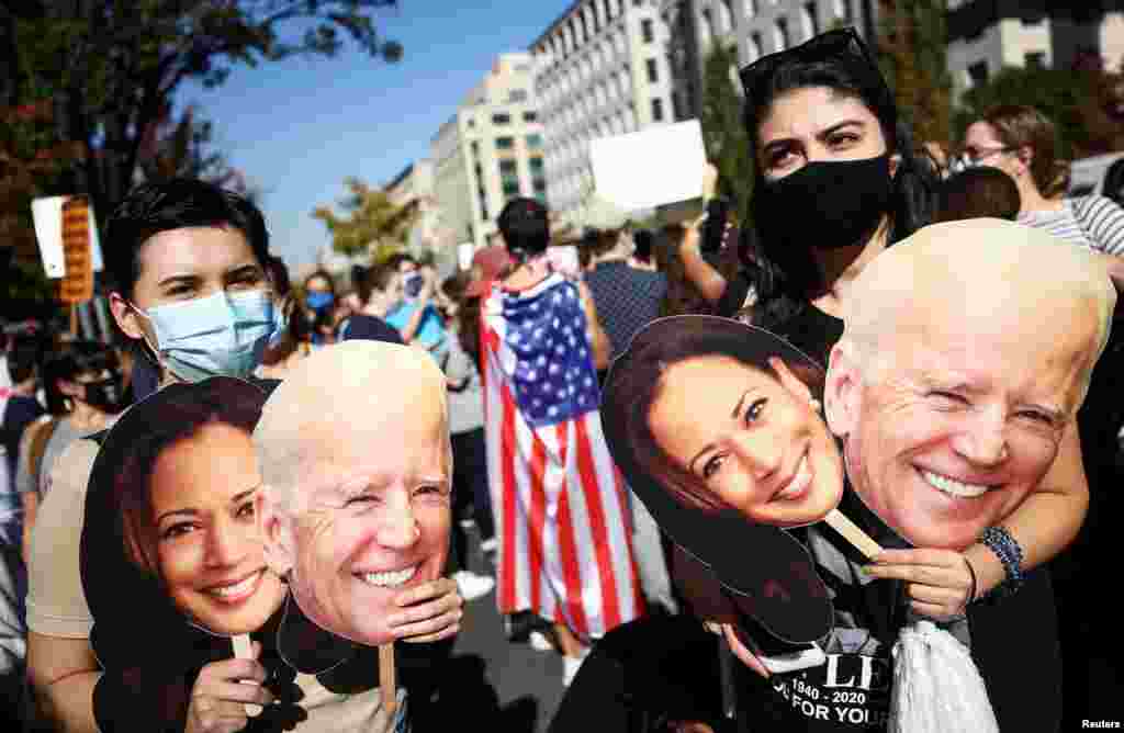 People hold cardboard cutouts after media announced that Democratic U.S. presidential nominee Joe Biden has won the 2020 U.S. presidential election, on Black Lives Matter Plaza near the White House.