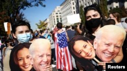 People hold cardboard cutouts after media announced that Democratic U.S. presidential nominee Joe Biden has won the 2020 U.S. presidential election, on Black Lives Matter Plaza near the White House.