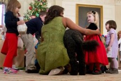 FILE - Then-first lady Michelle Obama and Bo, the Obamas' dog, are surrounded by children in the State Dining Room of the White House in Washington, Dec. 2, 2015. Bo died May 8, 2021, after a battle with cancer, the Obamas said.