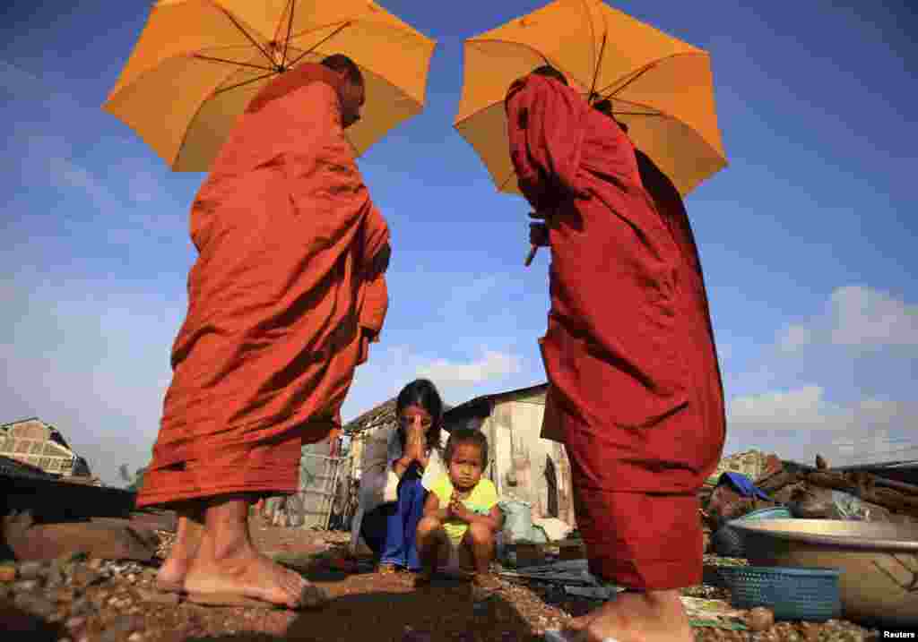 A woman and her daughter pray after offering alms to Buddhist monks near a railway track in Phnom Penh, Cambodia.