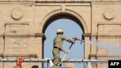 Seorang petugas damkar menyemprotkan cairan disinfektan di Gerbang India saat pemberlakuan karantina nasional untuk mencegah penularan COVID-19 di New Delhi, 17 April 2020. (Foto: AFP)