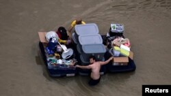 Residents wade with their belongings through flood waters brought by Tropical Storm Harvey in Northwest Houston, Texas, U.S. August 30, 2017. 