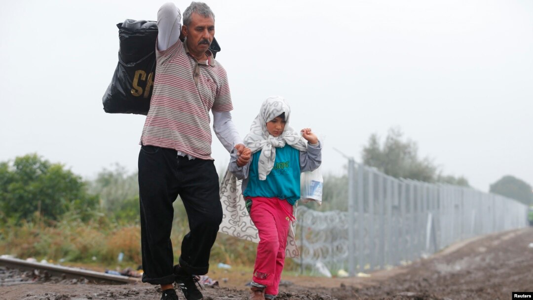 Migrants walk along a railway track as they cross the Hungarian border with Serbia near a collection point in Roszke, Hungary, Sept. 11, 2015.
