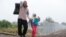 Migrants walk along a railway track as they cross the Hungarian border with Serbia near a collection point in Roszke, Hungary, Sept. 11, 2015.