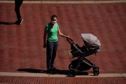 FILE - A view of young mother pushing a stroller during the coronavirus pandemic on May 20, 2020, in Bethesda Fountain, Central Park in New York City.