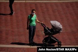FILE - A view of young mother pushing a stroller during the coronavirus pandemic on May 20, 2020, in Bethesda Fountain, Central Park in New York City.