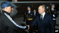 Президент Росії Володимир Путін вітає засудженого за вбивство Вадима Красикова після прибуття звільнених російських ув'язнених в аеропорту Внуково під Москвою, Росія, 1 серпня 2024 року. Mikhail Voskresensky, Sputnik, Kremlin Pool Photo via AP