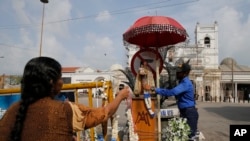 Seorang tentara Angkatan Laut Sri Lanka membantu seorang warga Katolik meletakkan karangan bunga di luar Gereja St.Anthonius, salah satu lokasi yang menjadi target pengeboman di Kolombo, Sri Lanka, 5 Mei 2019. (Foto: dok)