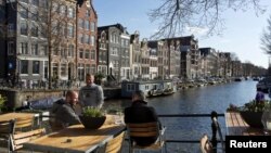 FILE - Men enjoy the afternoon sun at the Brouwersgracht canal in Amsterdam, April 2, 2013. 