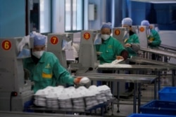 FILE - Workers are seen on a production line manufacturing masks at a factory in Shanghai, China, Jan. 31, 2020.