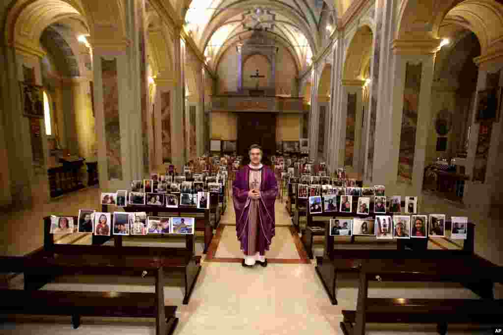 Robbiano Church parson, Don Giuseppe Corbari, poses next to selfies sent by his parishioners and pasted on the pews of the Robbiano church, as Masses for the faithful have been suspended following Italy&#39;s coronavirus emergency, in Giussano.