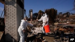 Katelyn White, a la izquierda, y su marido John Borbone revisan su propiedad devastada por el fuego tras el incendio de Palisades, en el barrio de Pacific Palisades de Los Ángeles, el martes 28 de enero de 2025.