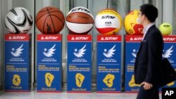 A man walks by advertisement displays of the official balls for 2014 Incheon Asian Games at the 2014 Incheon Asian Games Organizing Committee in Incheon, west of Seoul, South Korea, May 23, 2014.