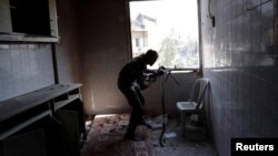 A fighter of Syrian Democratic Forces takes up position inside a building during a battle with Islamic State militants at the frontline in Raqqa, Syria, Oct. 7, 2017.