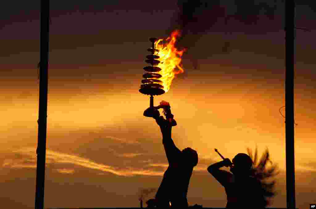 June 17: A Hindu priest holds a traditional oil lamp as he performs prayers on the banks of the River Ganges in Allahabad, India. (AP Photo/Rajesh Kumar Singh)