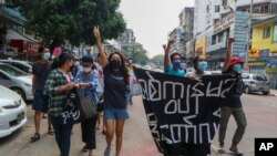 Anti-coup protesters shout slogan with a banner reading ''Carry on revolution! We do not accept as the military slave,'' in Kamayut township of Yangon, Myanmar, Monday, April 19, 2021. Anti-coup protesters kept public demonstrations going despite…