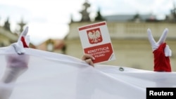 FILE - A demonstrator holds a copy of the Polish Constitution during a protest against judicial reforms, outside the Presidential Palace in Warsaw, Poland, July 3, 2018. 