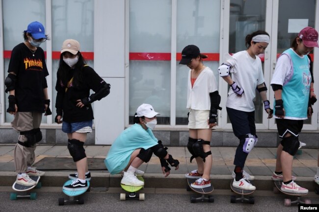 Members of Beijing Girls Surfskating Community stand on skateboards as they attend a training session for beginners, outside the National Sports Stadium in Beijing, China June 19, 2022. (REUTERS/Tingshu Wang)