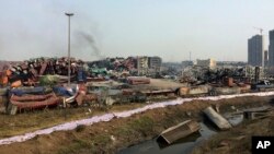 FILE - Smoke rises from damaged container boxes near the site of an explosion at a warehouse in northeastern China's Tianjin municipality, Aug. 17, 2015.