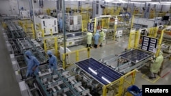 FILE - Workers assemble Photovoltaic Modules at the plant of Adani Green Energy Ltd in Mundra, India, April 11, 2024.