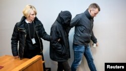A pedestrian walks down steps through a row of trees during a rainy autumn day, in Pamplona, northern Spain.
