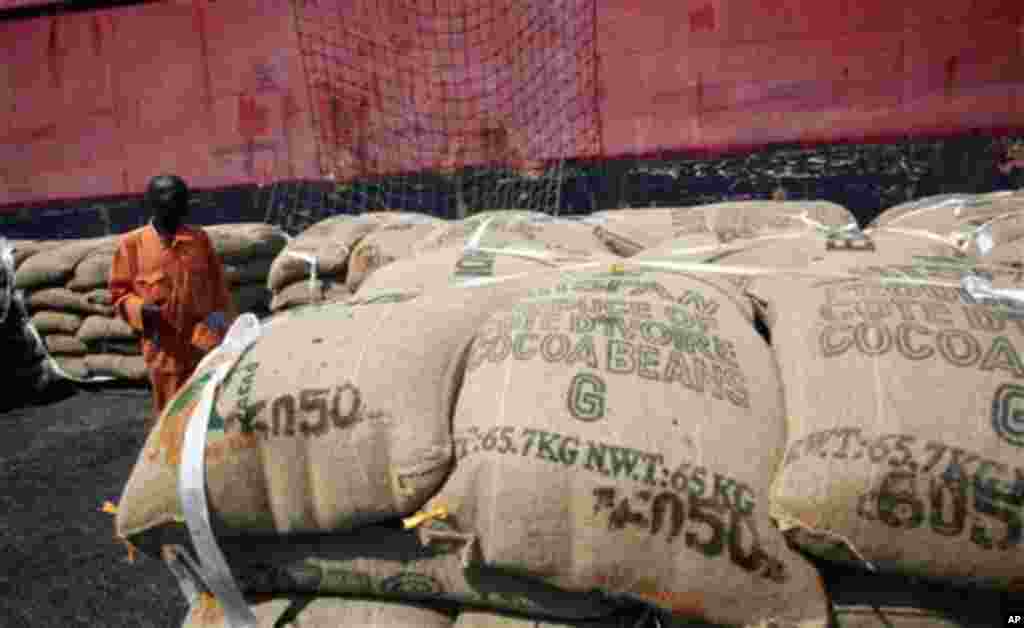 A worker stands among sacks of cocoa beans as they are loaded for shipment at the port in Abidjan, Ivory Coast, May 10, 2011.
