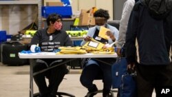 Elections workers at the Fulton County Georgia elections warehouse check in voting machine memory cards that store ballots following the Senate runoff election in Atlanta on Tuesday, Jan. 5, 2021. Georgia's two Senate runoff elections on Tuesday…