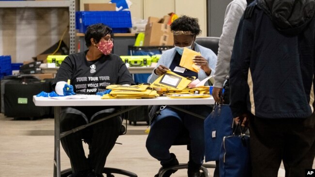 Elections workers at the Fulton County Georgia elections warehouse check in voting machine memory cards that store ballots following the Senate runoff election in Atlanta on Tuesday, Jan. 5, 2021. Georgia's two Senate runoff elections on Tuesday…