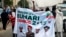 All Progressives Congress (APC) supporters hold a banner with a photograph of former military ruler Muhammadu Buhari in Lagos, Nigeria, Dec. 10, 2014.