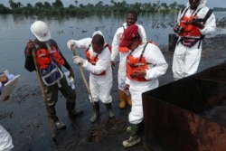 FILE - Members of the joint task force, part of the Bodo oil spill clean-up operation, inspect the site of an illegal refinery near the village of Bodo in the Niger Delta, Aug.2, 2018.