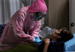 Dressed in protective gear to curb the spread of the new coronavirus, a medical worker attends to a patient at a military hospital set up to take care of COVID-19 patients in Mexico City, November 30, 2020.