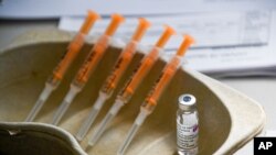 FILE - A vial and syringes with the AstraZeneca COVID-19 vaccine are seen at a makeshift inoculation site in Luton, England, March 21, 2021. The British government says it will begin rolling out COVID-19 booster shots in early September.
