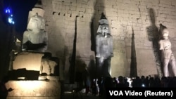 Tourists and Egyptians look at a huge granite statue of Ramses II,, center, after the completion of the restoration work, hours after the Egyptian Ministry of Antiquities revealed the contents of a Pharaonic cemetery on the western bank in Luxor, south of