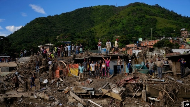 Los lugareños buscan llamar la atención del presidente de Venezuela, Nicolás Maduro, mientras visita el área dañada por las inundaciones en Las Tejerías, Venezuela, el lunes 10 de octubre de 2022. Un deslizamiento de tierra provocado por inundaciones tras días de lluvia torrencial arrasó esta ciudad en el centro de Venezuela. (Foto AP/Matías Delacroix)