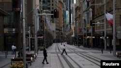 People in protective face masks walk through the quiet city center during a lockdown to curb the spread of COVID-19 outbreak in Sydney, Australia, July 28, 2021.