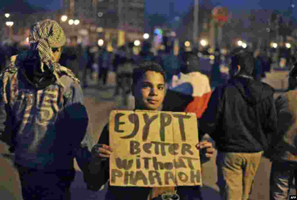 An anti-government protester holds a placard referring to Egyptian President Hosni Mubarak and reading "Egypt Better without Pharaoh" at night during the continuing demonstration in Tahrir square in downtown Cairo, Egypt, Tuesday, Feb. 1, 2011. More than 