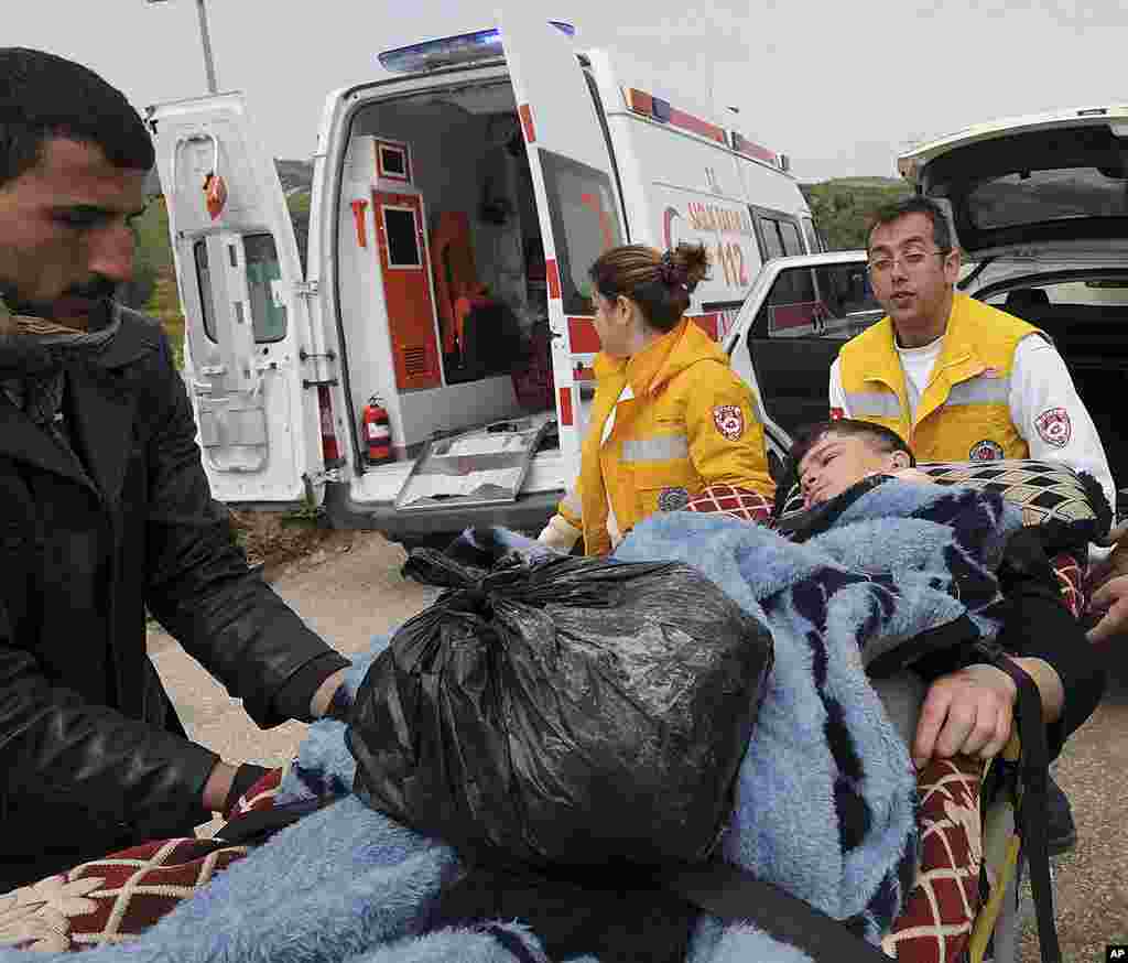 Turkish medics and a Syrian man carry a newly arrived injured Syrian refugee boy to a waiting ambulance in Hapipasa village in Hatay, Turkey, March 12, 2012. (AP)