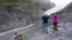 FILE - A sign marks where the end of the Exit Glacier was in 2010 near tourists taking photos in the Kenai Fjords National Park, Alaska, Aug. 31, 2019.