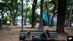 ARCHIVO - Una persona que lava autos para recibir propinas descansa en un banco del parque en la plaza Uruguay en una tarde calurosa en Asunción, Paraguay, el viernes 17 de enero de 2025. AP