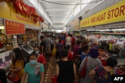 FILE - Customers visit a wet market to buy food in Singapore on April 4, 2020, with some people wearing facemasks due to concerns over the spread of the COVID-19 coronavirus.