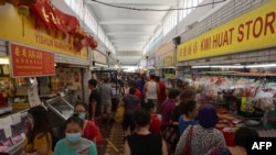 Customers visit a wet market to buy food in Singapore on April 4, 2020, with some people wearing facemasks due to concerns over the spread of the COVID-19 coronavirus. 