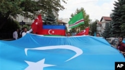 FILE - Uighurs living in Turkey carry a blue flag with a white star and a crescent representing Eastern Turkistan in Ankara, Turkey, July 5, 2012.