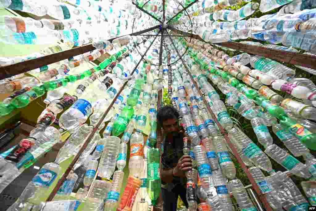 A man arranges used plastic bottles for an installation, in Chennai, India.