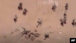 Des images, prises par un drone, montrent des soldats s'affairer autour de cadavres qu'ils recouvrent de sable. (capture d'écran)