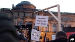 FILE - A demonstrator carries a mock gallows with nooses, marked "Reserved for Angela Merkel" and "Reserved for Sigmar Gabriel," her deputy, in PEGIDA (Patriotic Europeans against the Islamization of the West) protest in Dresden, Germany, Oct. 12, 2015.